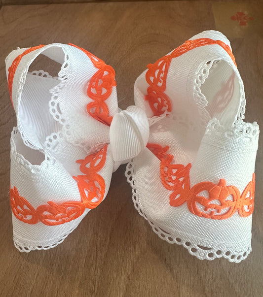 White boutique hair bow with scalloped lace edges and bright orange jack-o-lantern trim design.